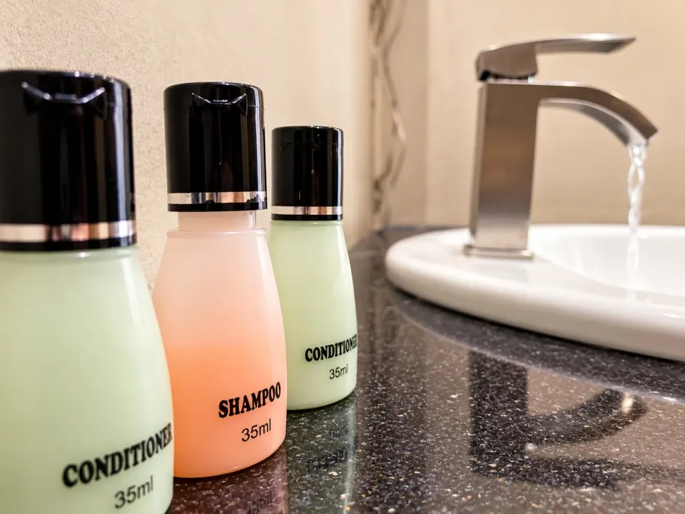 Hotel Toiletries by a Running Sink